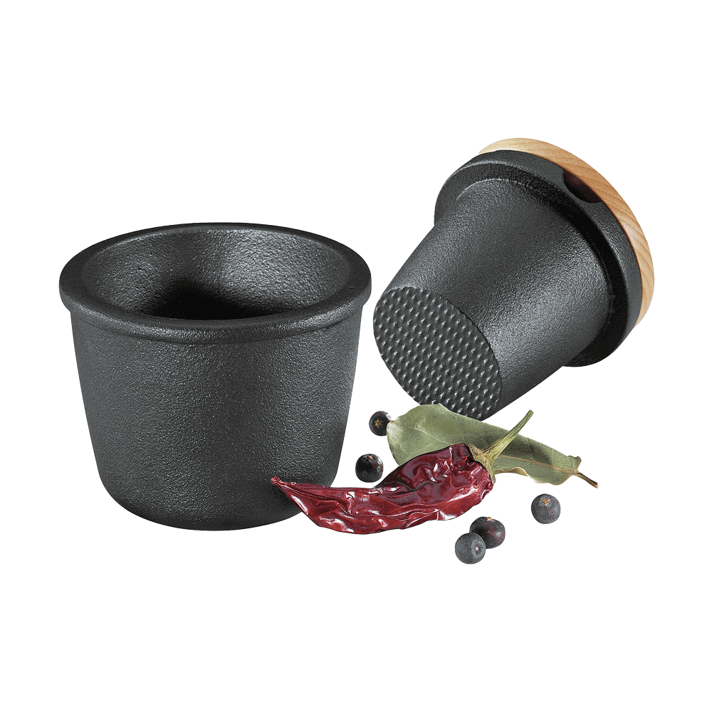 Gewürzreibe Gusseisen Gewürzreibe aus Gusseiesen. Der Mahlkonus liegt neben der Schale, davor liegen Pefferkörner und Paprika, ohne Hintergrund.