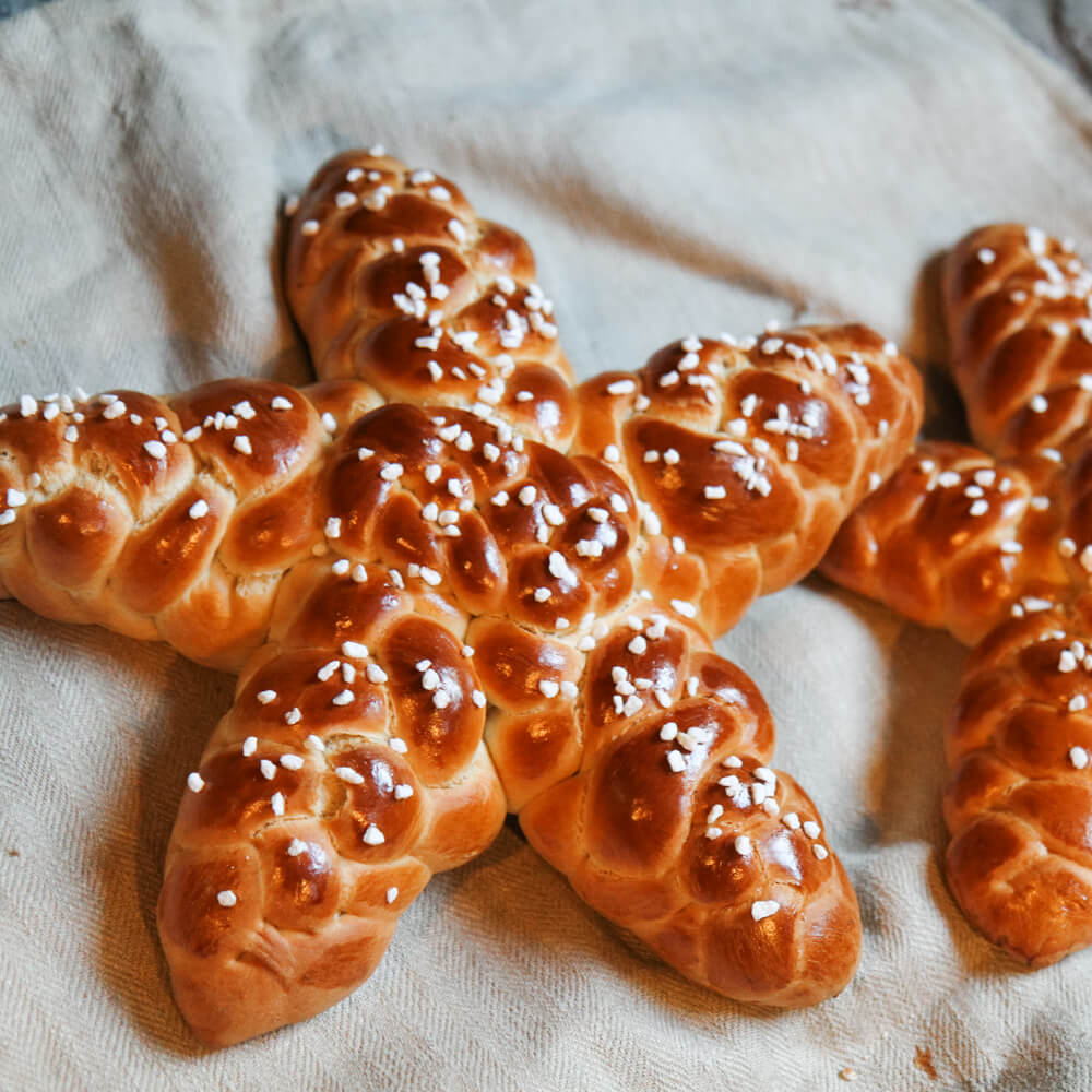 Rezept für Sternzöpfe Hefezöpfe in Sternform. mit Hagelzucker bestreut auf einem Grauentuch