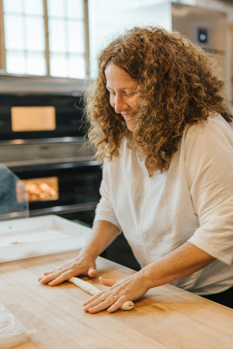 Bäckermeisterin rollt den Teig zur einer Stange