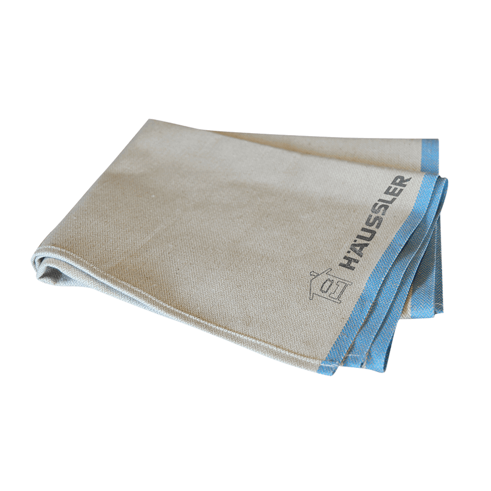 Französisches Bäckerleinen Leinentuch mit blauem Rand und aufgedrucktem Häussler-Logo, gefaltet, ohne Hintergrund.