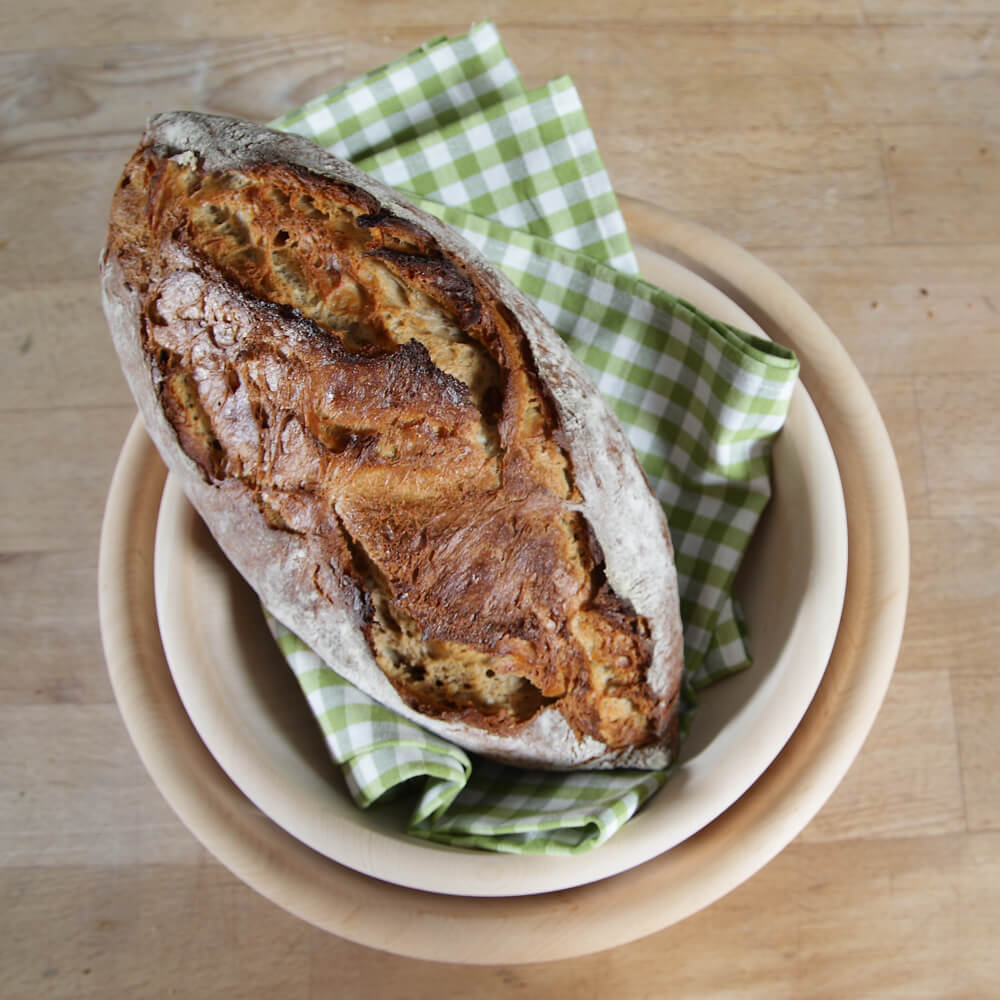 Rezept für Bierbrot selbstgemachtes Bierbrot in einer Holzschale mit grün kariertem Geschirrtuch