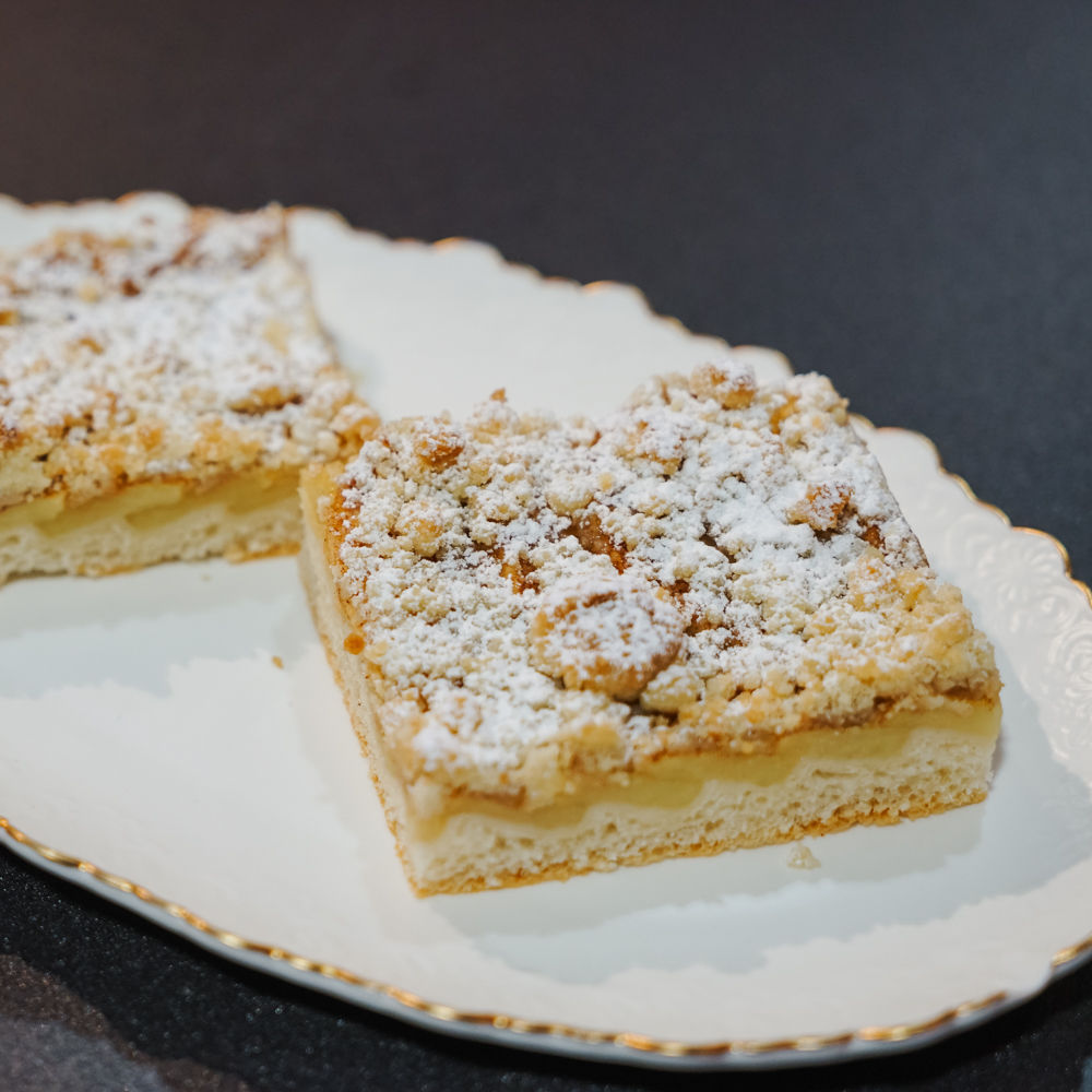 saftiger Apfelkuchen mit Streuseln auf einer weißen Platte serviert