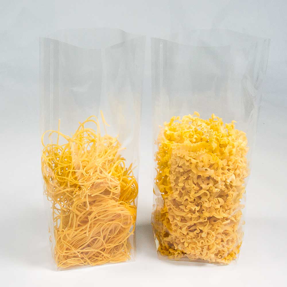 Nudel- und Plätzchenverpackung 17,0 x 28,0 cm Zwei Nudel- und Plätzchenverpackungen aus transparenter Folie gefüllt mit zwei verschiedenen Nudelsorten vor einem weißen Hintergrund.
