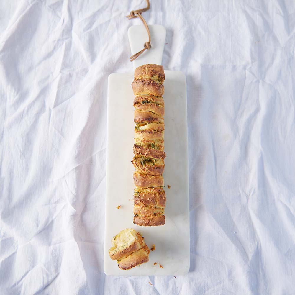 leckeres Zupfbrot mit Kräuterbutter auf einem Holzbrett serviert