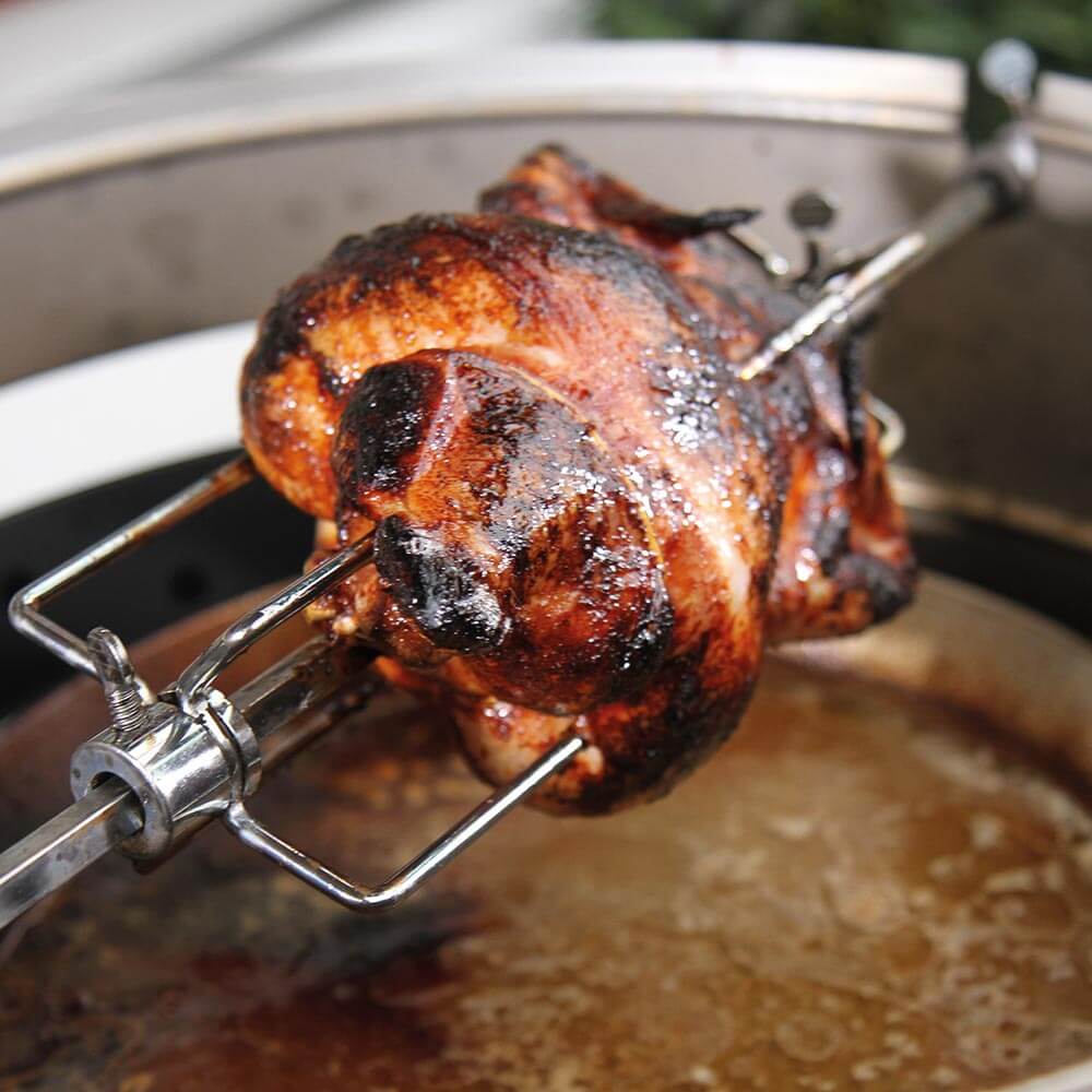 Gegrilltes Hähnchen auf elektrischem Grillspieß über einer Tropfschale 