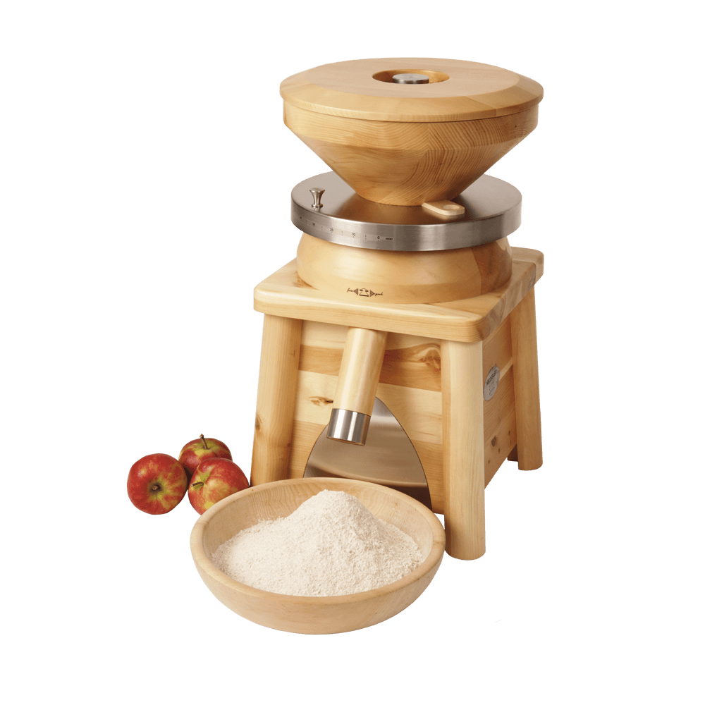 Getreidemühle Molly Getreidemühle Molly aus Zirbelholz mit einer Schüssel voll frisch gemahlenem Mehl und drei Äpfeln ohne Hintergrund