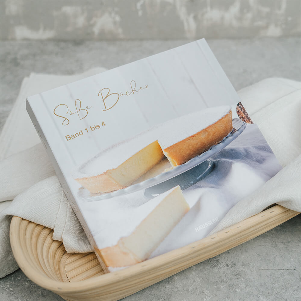 Backbuch-Set: Süße Bücher Band 1-4 Backbuch-Set. Die Faltschachtel, gefüllt mit den 4 Backbüchern liegt in einem mit einem Leintuch gefüllten Gärkorb