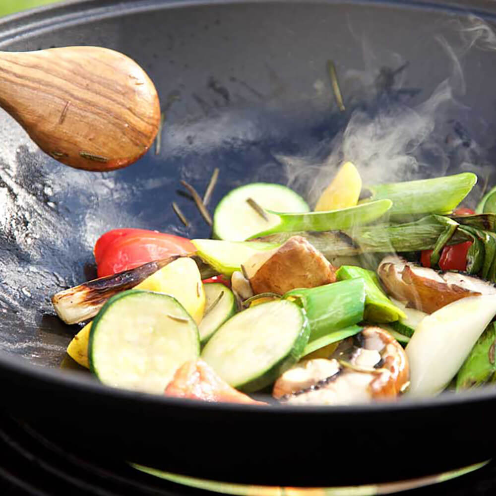Wok aus Gusseisen mit Deckel Gemüse im Wok das auf dem Grill zubereitet wird