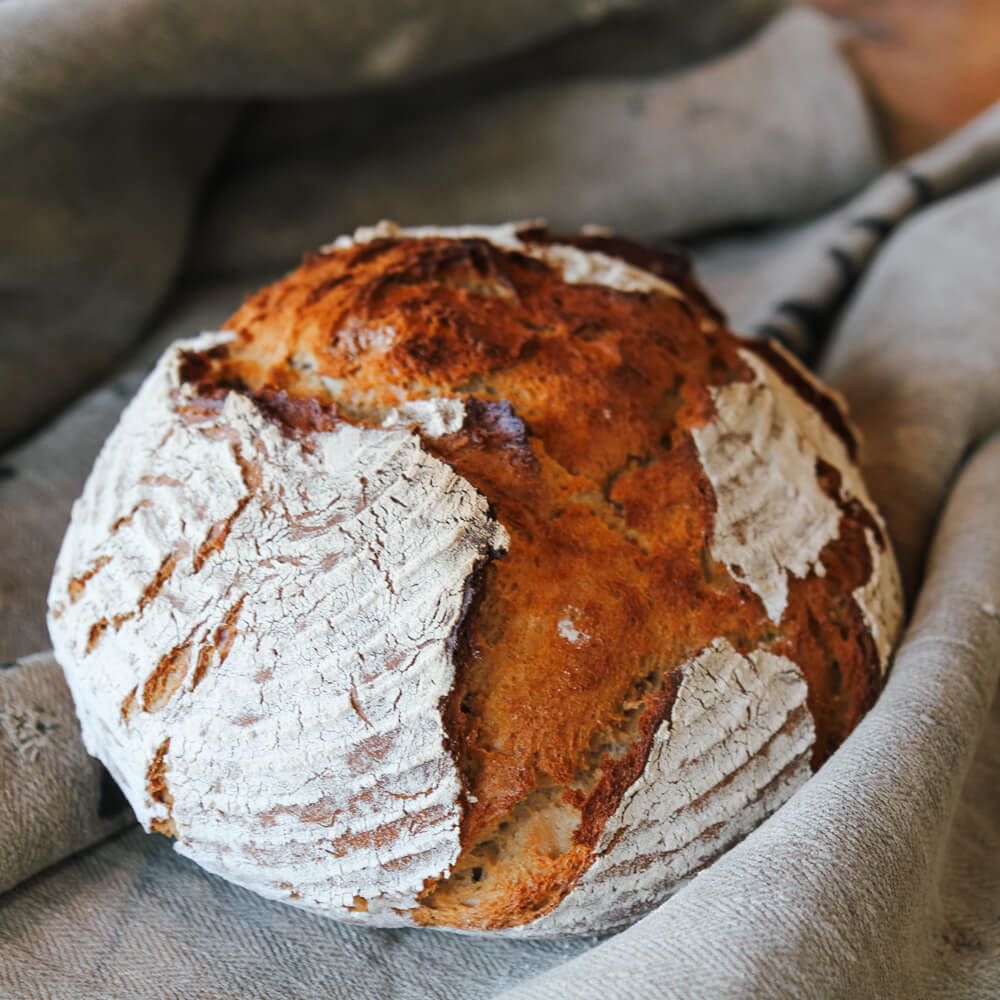 Rezept für Dinkelkruste Dinkelkruste mit Mehl eingestäubt auf einem grauen Tuch