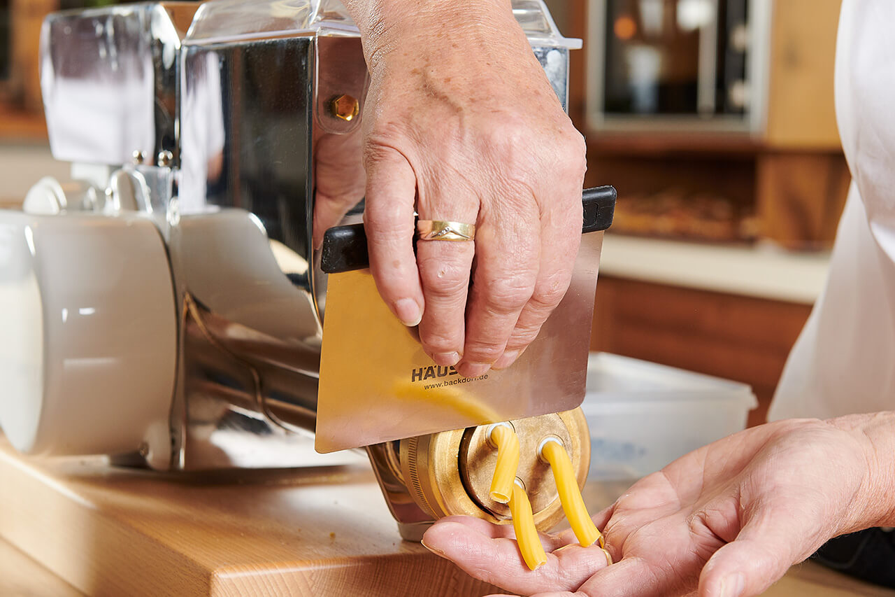 Nudelherstellung Frische Nudeln werden direkt an der Nudelmaschine mit einem Teigschneider abgeschnitten.