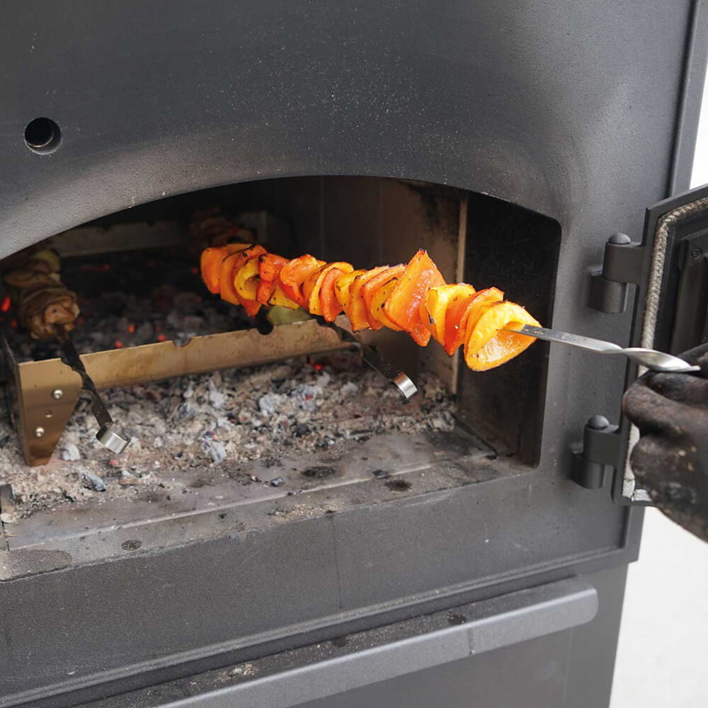 Grillrost und Grillspiieße im Holzbackofen mit Fleisch und Gemüse