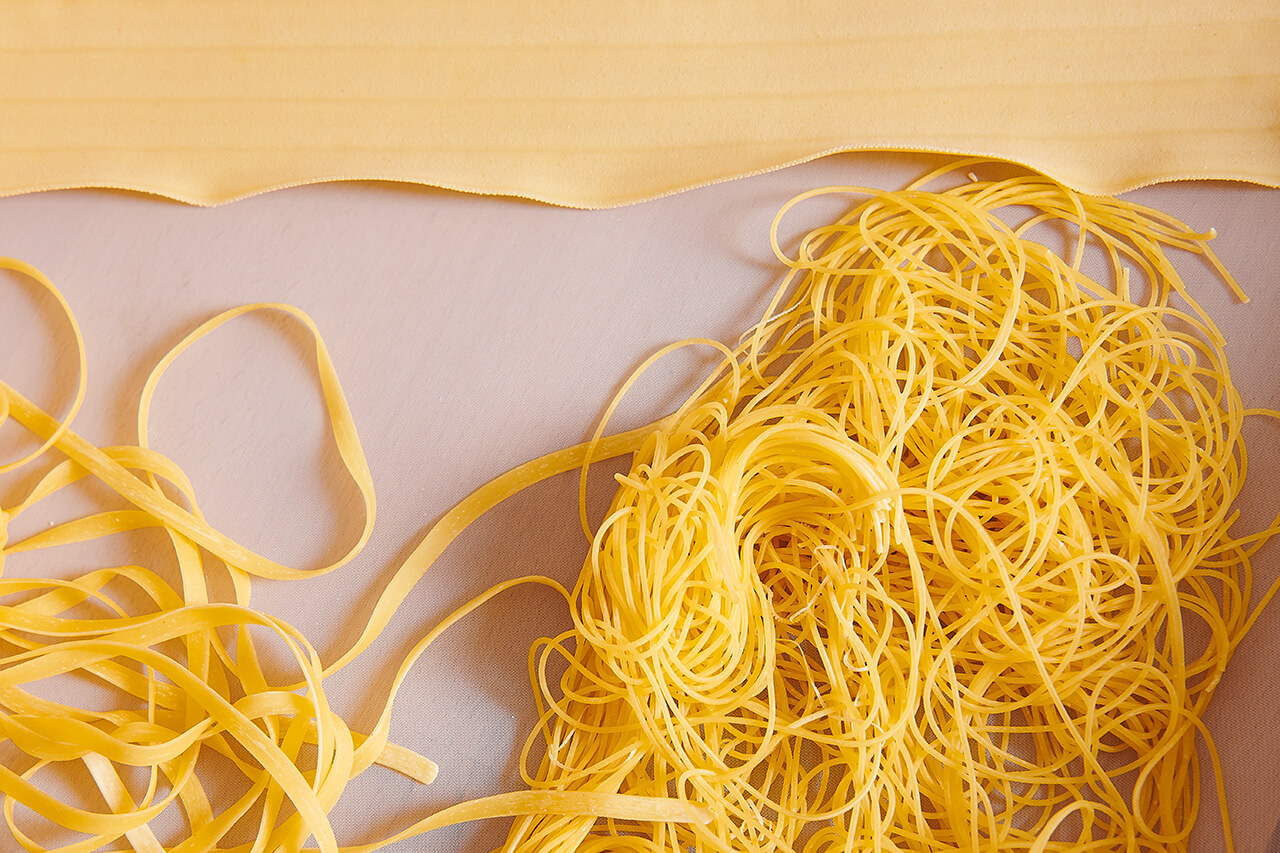 Frische Pasta auf einem Tisch ausgebreitet - hausgemachte Nudeln bereit zum Kochen.