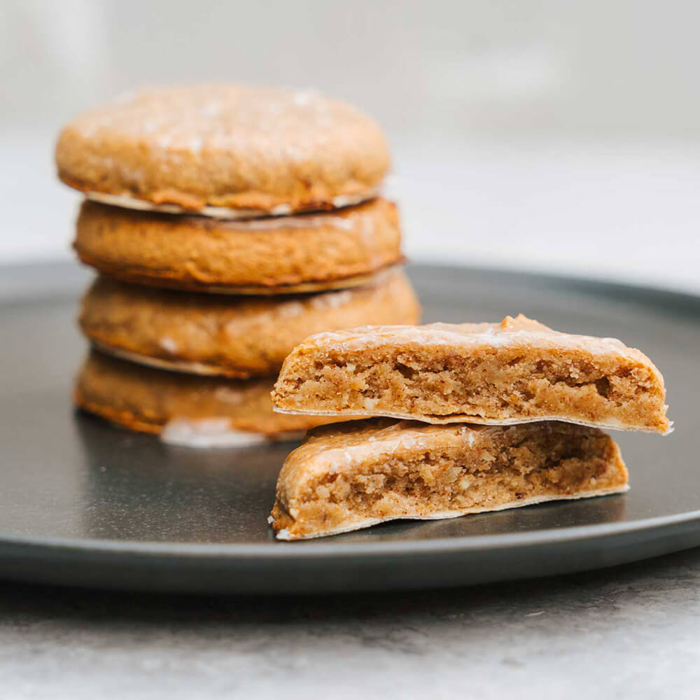 Backoblaten rund 50mm Auf einem schwarzen Teller liegen vier Elisenlebkuchen aufeinandergestapelt und daneben liegen zwei halbe Elisenlebkuchen aufeinander