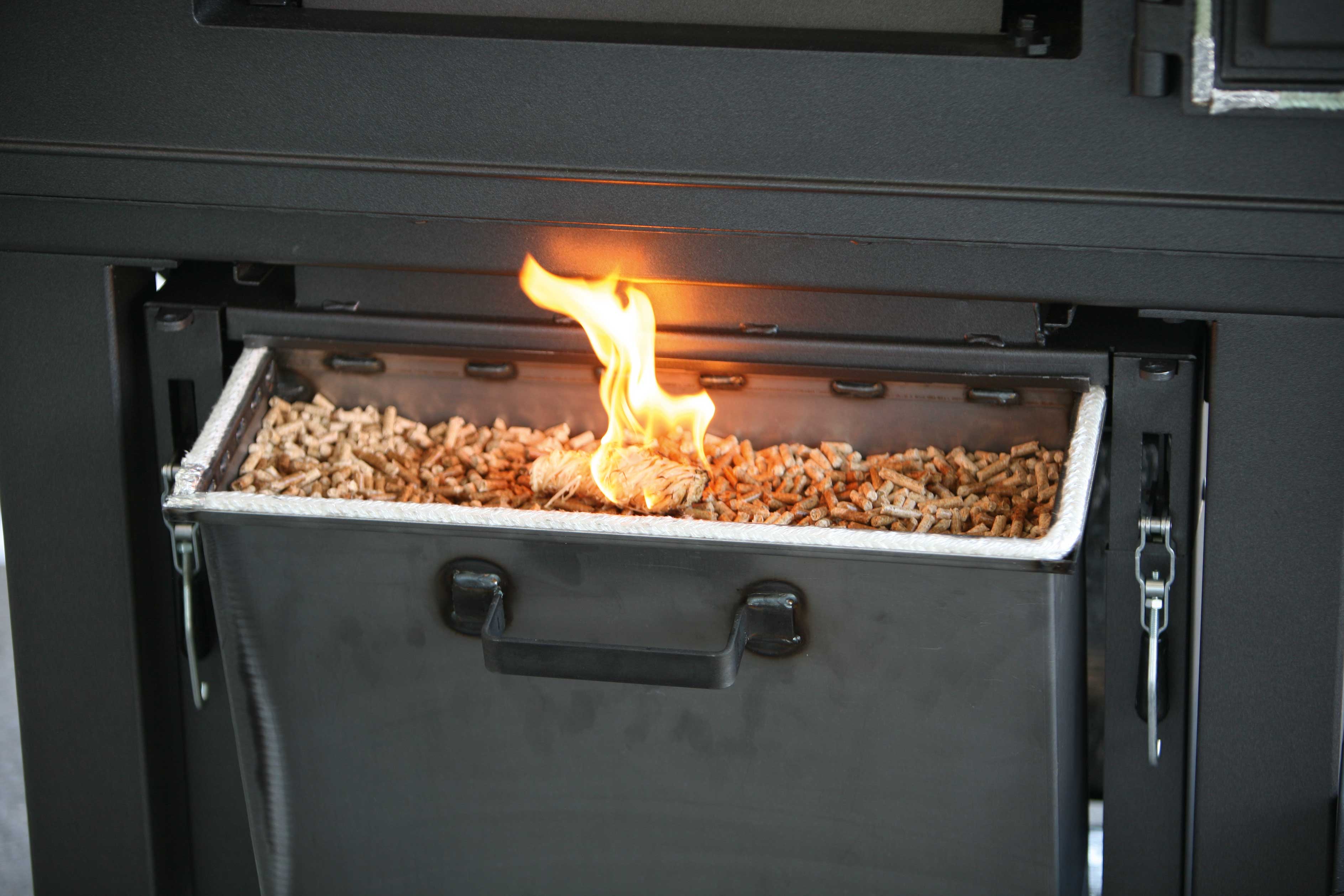 Brennerkassette für den Holzbackofen Brennerkassette an einem Holzbackofen. Die Pellets in der Kassette werden gerade mit einem Feueranzünder angezunden