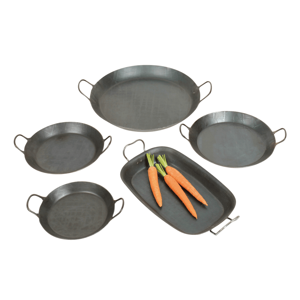 Geschmiedete Eisenbratpfanne mit 2 Griffen Fünf Eisenpfannen in verschiedenen Größen mit zwei Griffen. Vier Pfannen sind rund eine Pfanne ist Rechteckig. In der Recheckigen Pfanne liegen Karotten. Außerdem sind Tomaten, Zwiebeln und eine Zucchini zu sehen.