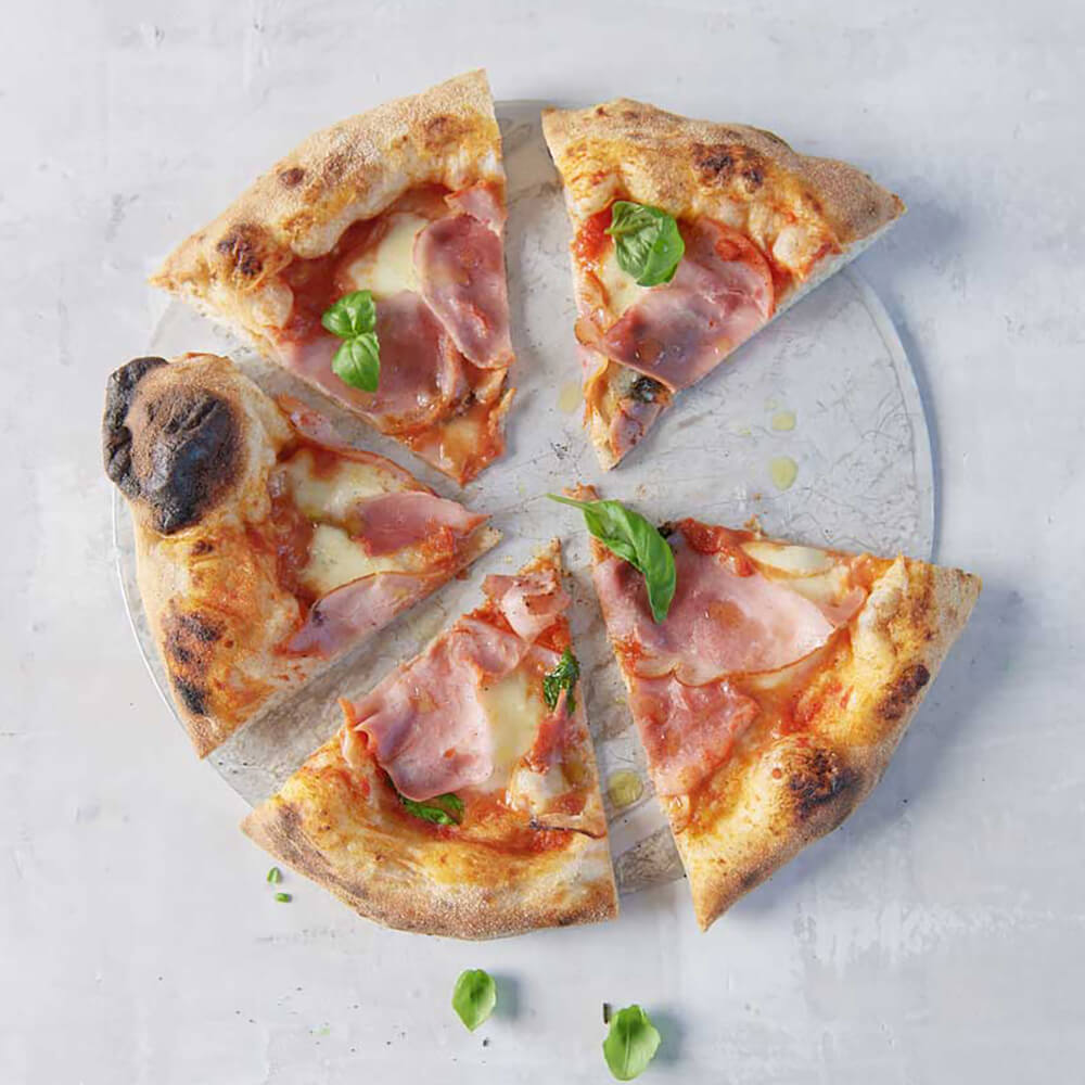 Frisch gebackene Pizza auf einem Glasteller, welche mit der Pizzaschere geschnitten wurde, auf einer Küchenarbeitsplatte.