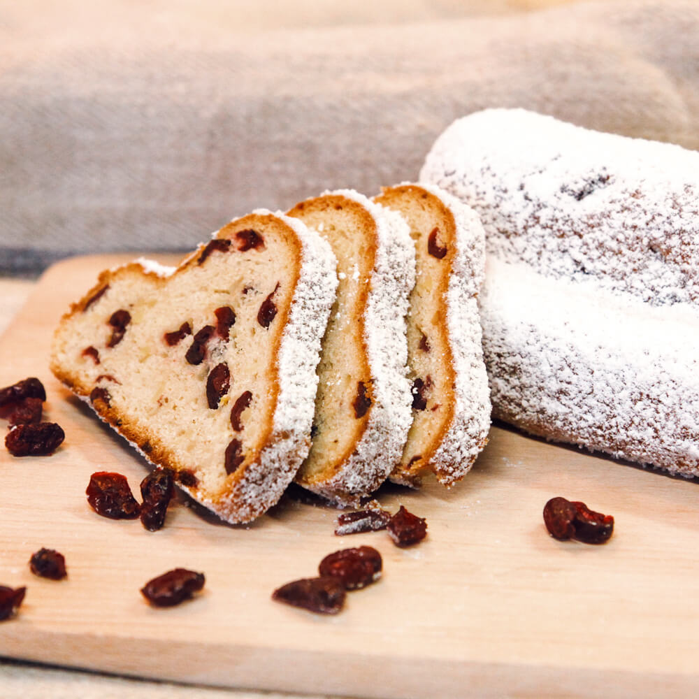 Rezept für Dinkel Christstollen mit Cranberries leckerer Christstollen mit Cranberrys und Puderzucker Bestreut auf einem Holzbrett