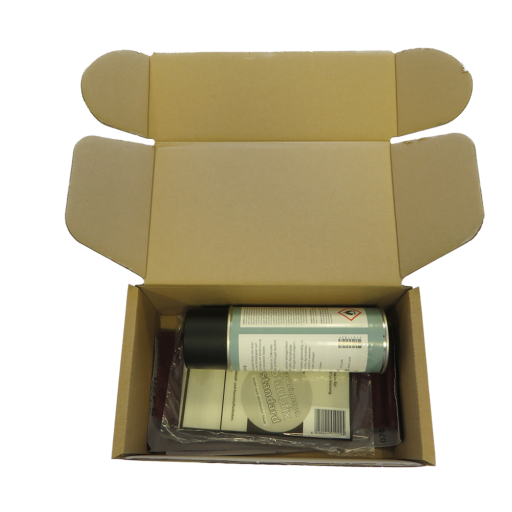 geöffneter brauner Karton in dem sich ein Ausbesserungsset für den Holzbackofen befindet.