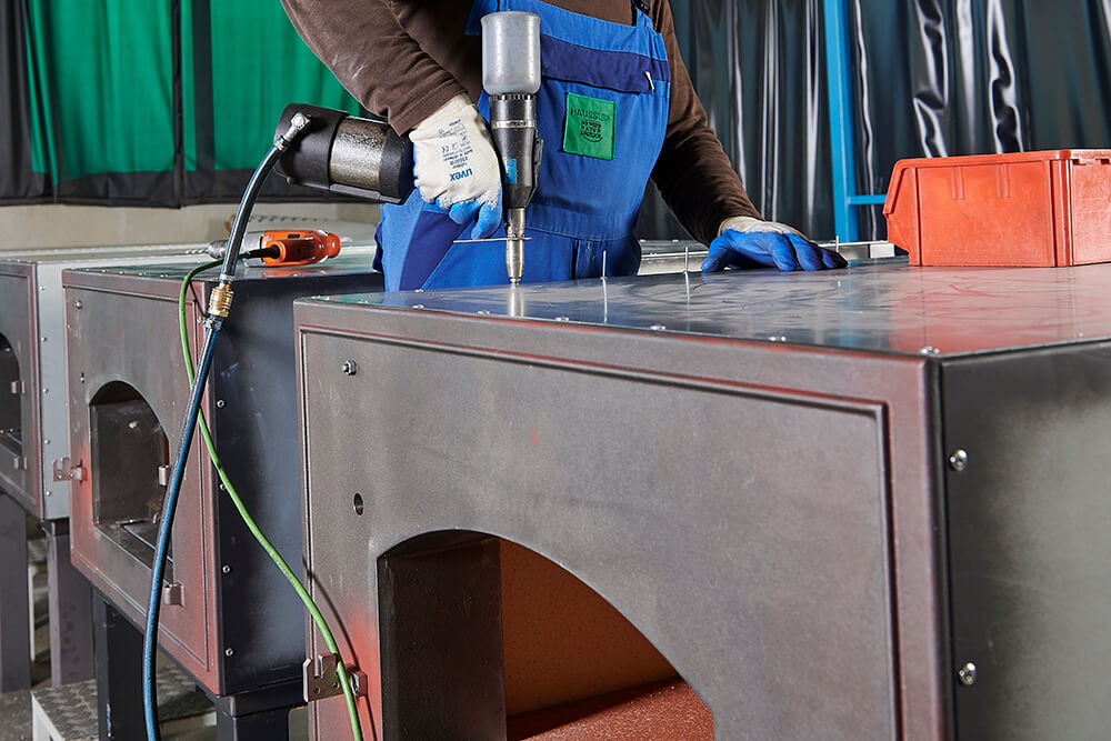 Handwerker befestigt Schrauben Handwerker befestigt Schrauben am Ofenkorpus während der Montage eines Holzbackofen