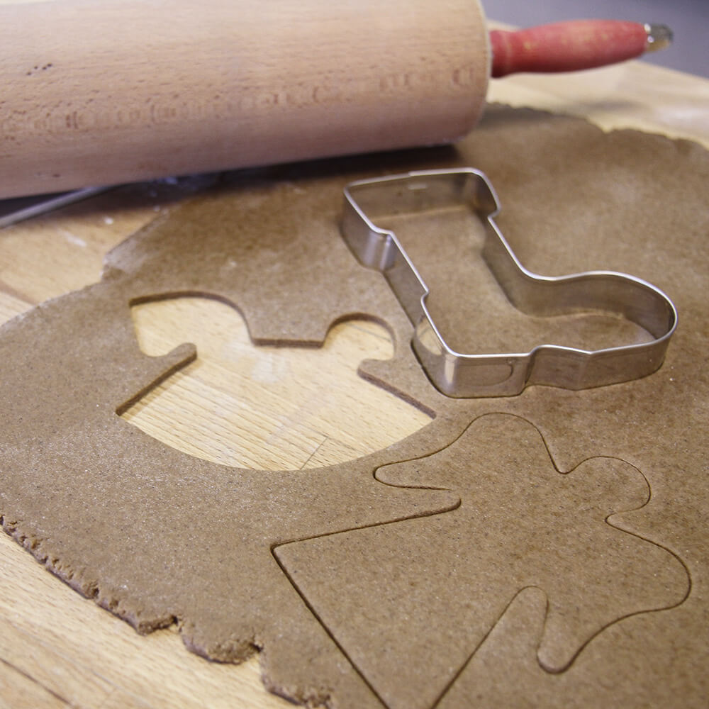 ausgerollter Plätzchenteig mit dem Ausstecher Schaukelpferd, Engel und Nikolausstiefel