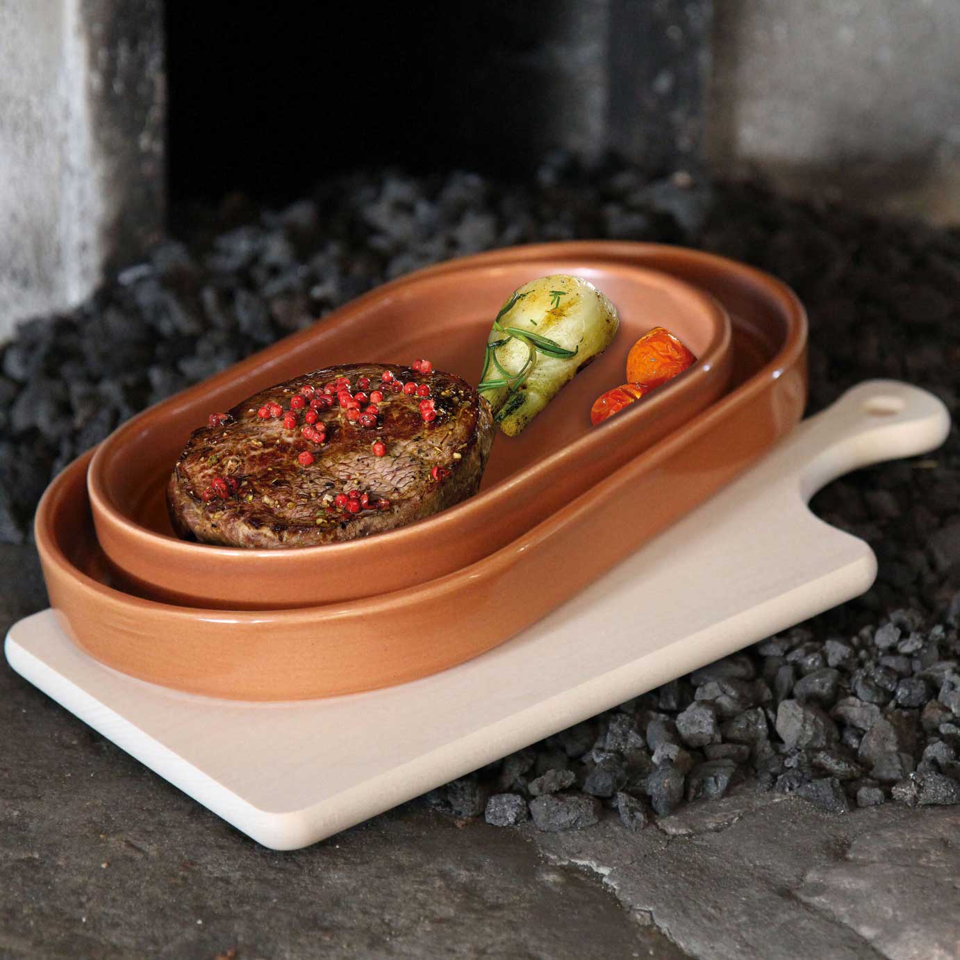 Servierbrett aus hellem Ahornholz. Auf dem Servierbrett befinden sich zwei ineinander gestellte Tonschalen mit Fleisch.