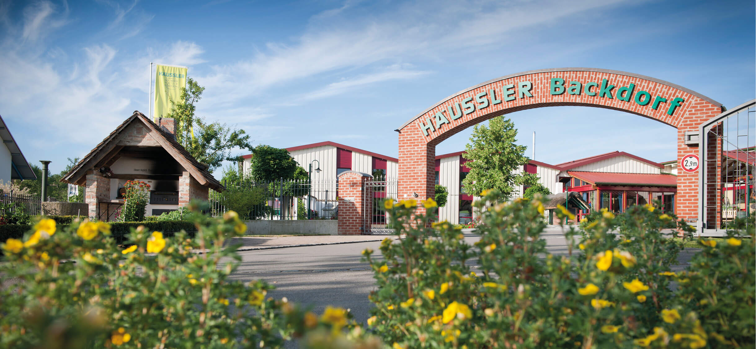 Aussenansicht des Backdorfs mit großem Eingangstor, traditioneller Architektur, Holz- und Steinelementen.