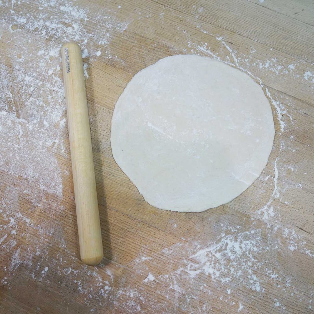 Rollholz aus Buche Rollholz aus Buche neben einem ausgerollten Teig auf einer bemehlten Arbeitsfläche.