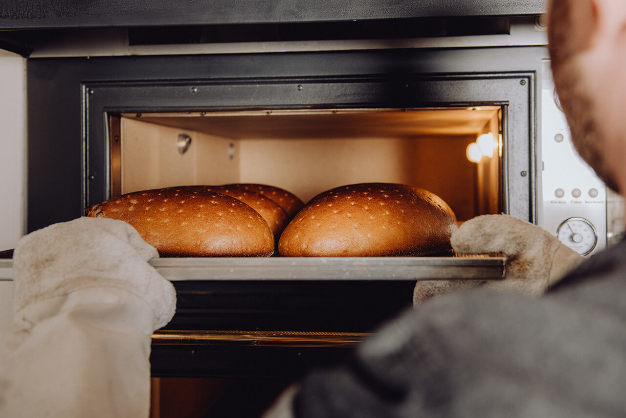 Bäcker holt frisch gebackenes Brot aus dem Elektro-Steinbackofen