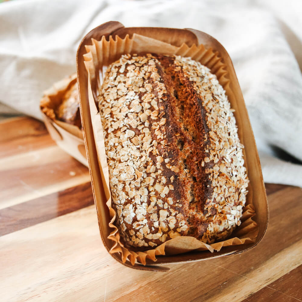 Rezept für Dinkelflockenbrot Dinkelflockenbrot in einer Holzbackform gebacken, auf einem Holzbrett serviert
