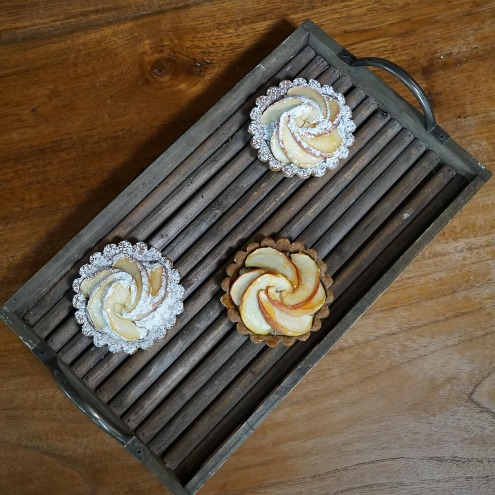 Rezept für Bratapfel-Spekulatius-Tartlettes Tartlettes mit einer Bratapfelfüllung und dünnen APfelscheiben garniert auf einem Backblech mit Rillen serviert