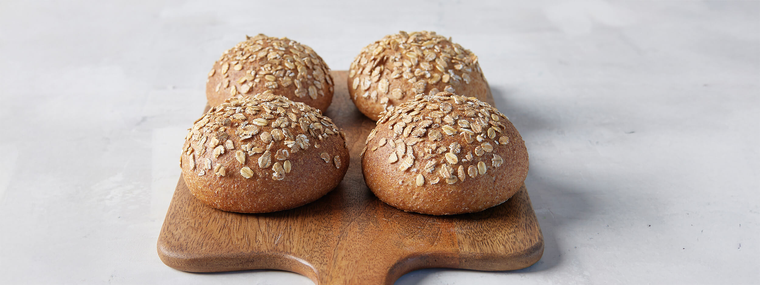 Vier Vollkornbrötchen auf einem Servierbrett