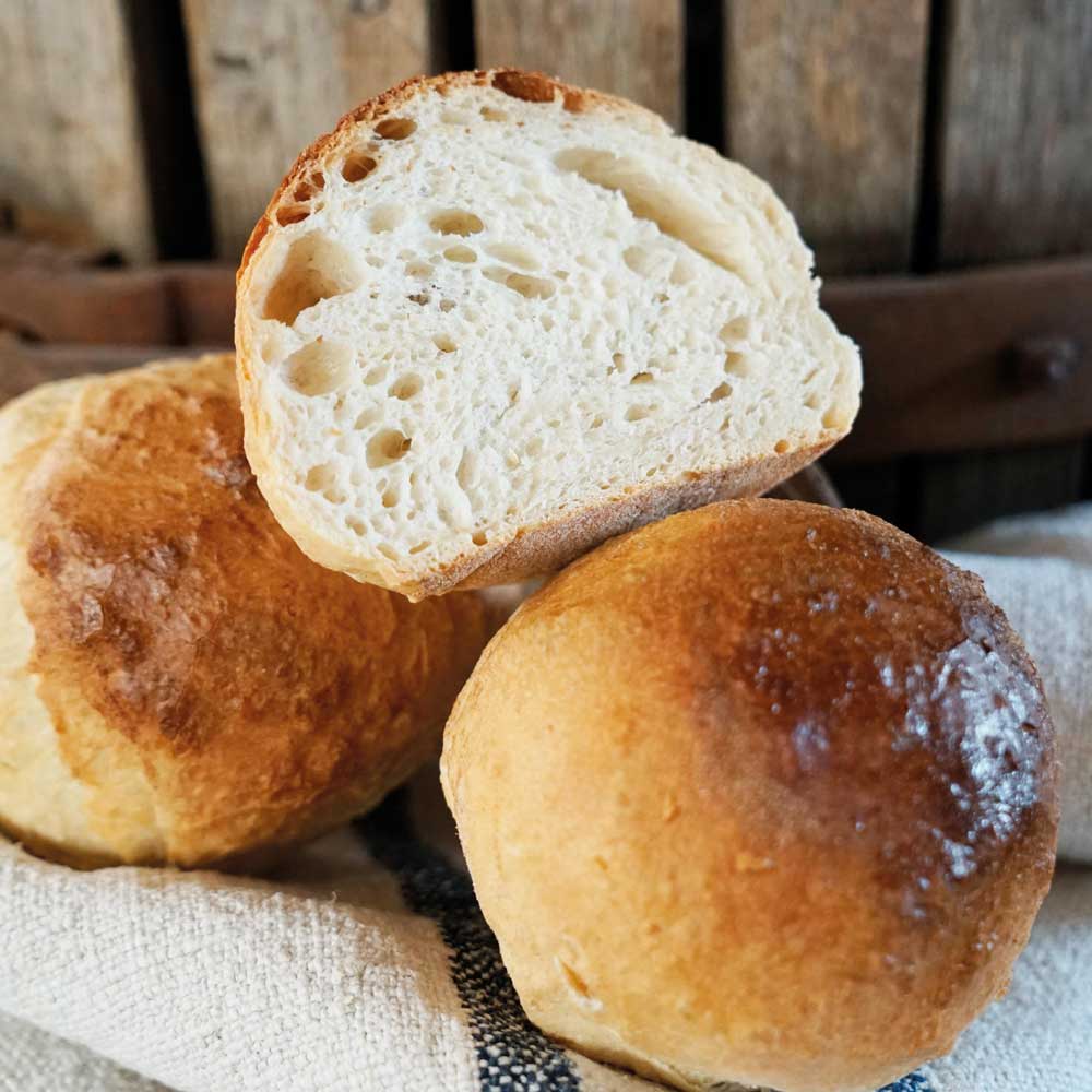 Frisch gebackene Knauzen aus dem Seelen- und Knauzenmehl auf einem Bäckerleinen vor einem hölzernen Hintergrund.