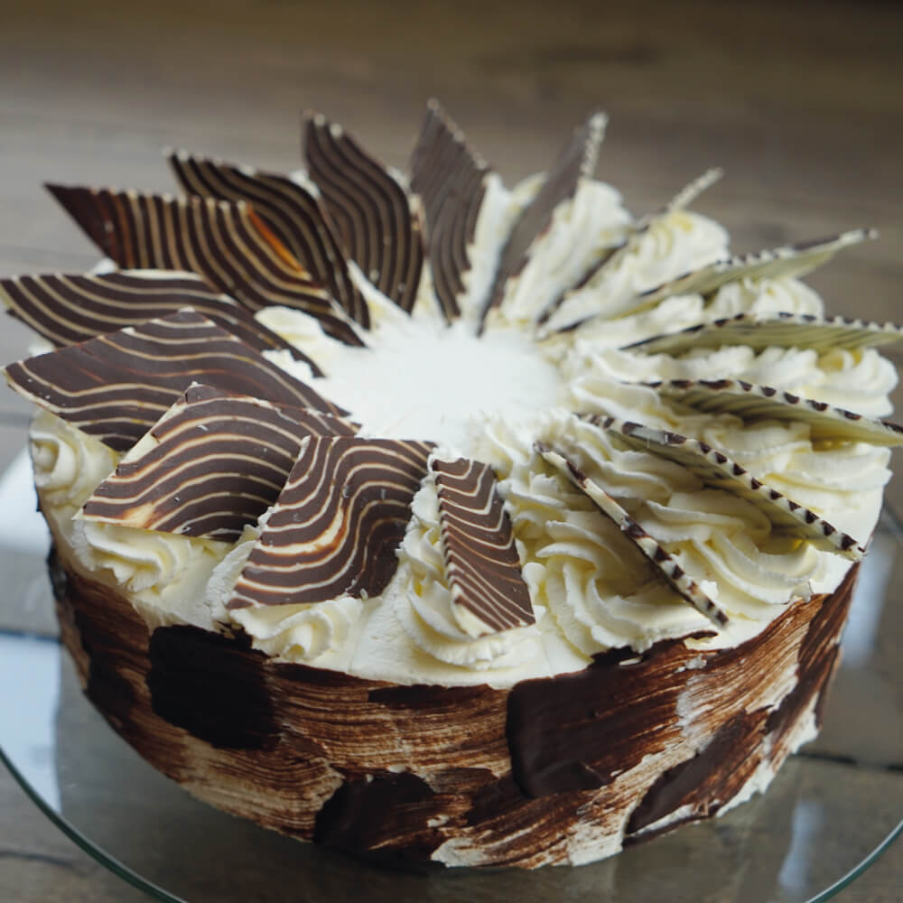 Rezept für Double-Chocolate-Torte selbstgemachte Torte mit heller und dunkler Schoko-Füllung. Eingestrichen mit Sahne und verziert mit dunkler und heller Schokolade in Rautenform dekoriert.