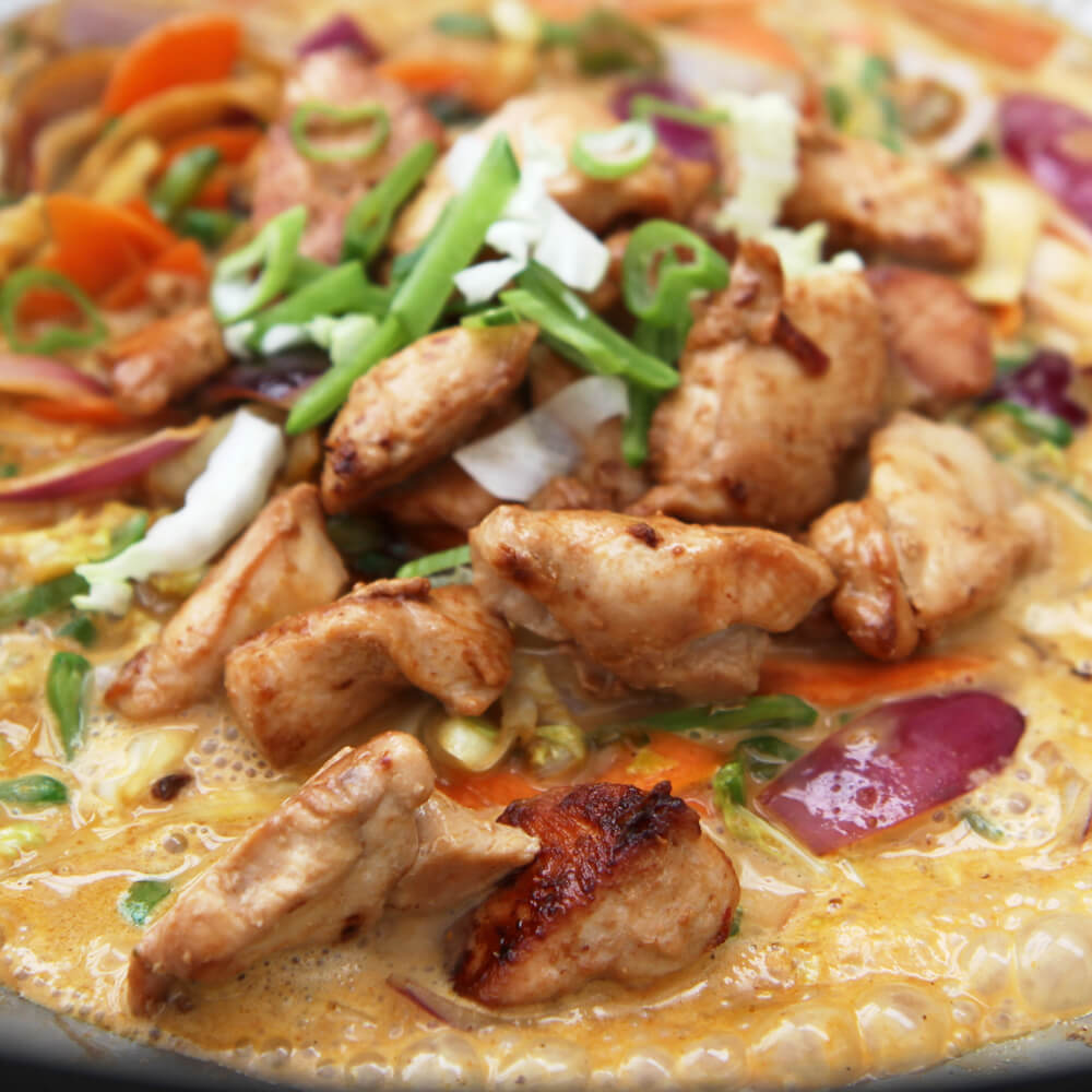 Rezept für Hähnchencurry Hähnchencurry mit gewürfeltem Hähnchen, Zwiebeln, Paprika und Kokosmilch in einem Wok serviert