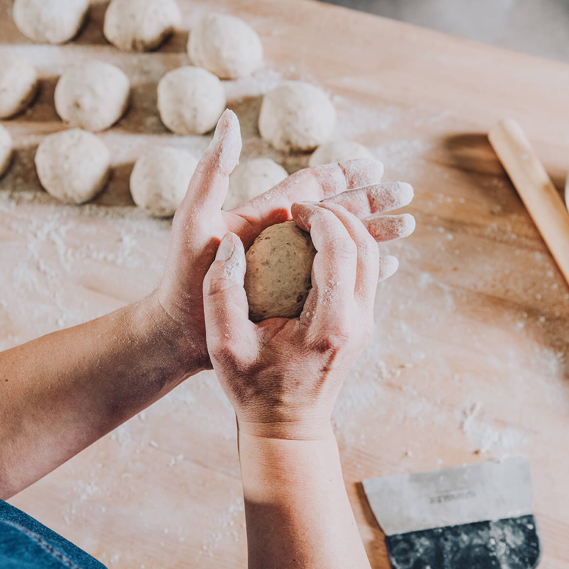 Bäcker formt Teiglinge Bäcker formt Teiglinge von Hand auf einer bemehlten Arbeitsfläche- traditionelles Handwerk im Backdorf