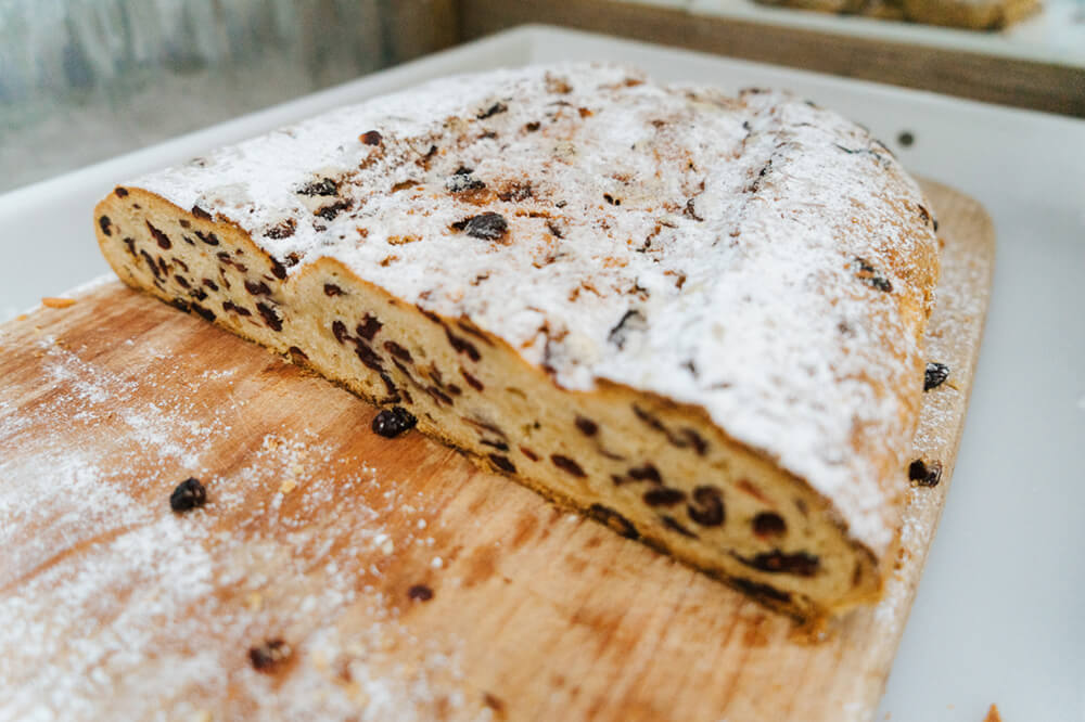 Adventskaffe mit Kuchen und Stollen Stollen mit Rosinen angeschnitten auf einem Schneidebrett