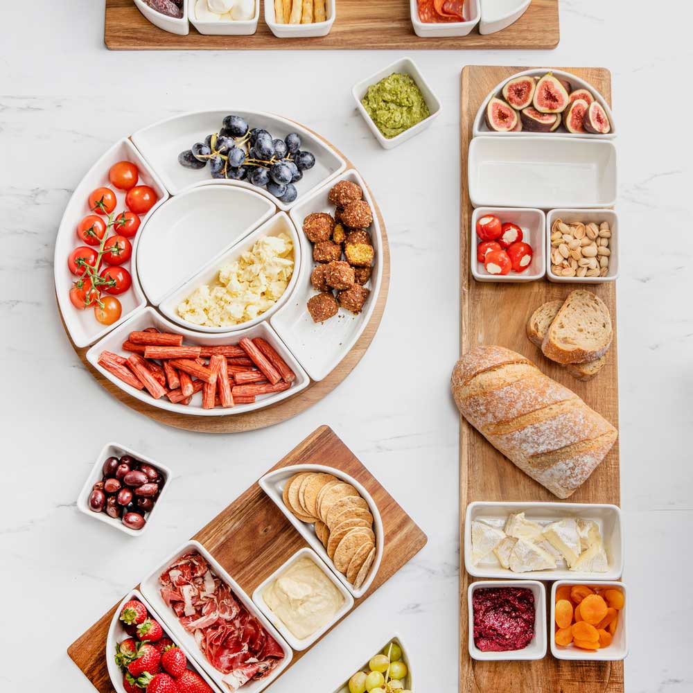 Drehteller und einige Servierbretter, alle gefüllt mit verschiedenen Snacks von oben fotografiert auf einer Küchenarbeitsplatte.