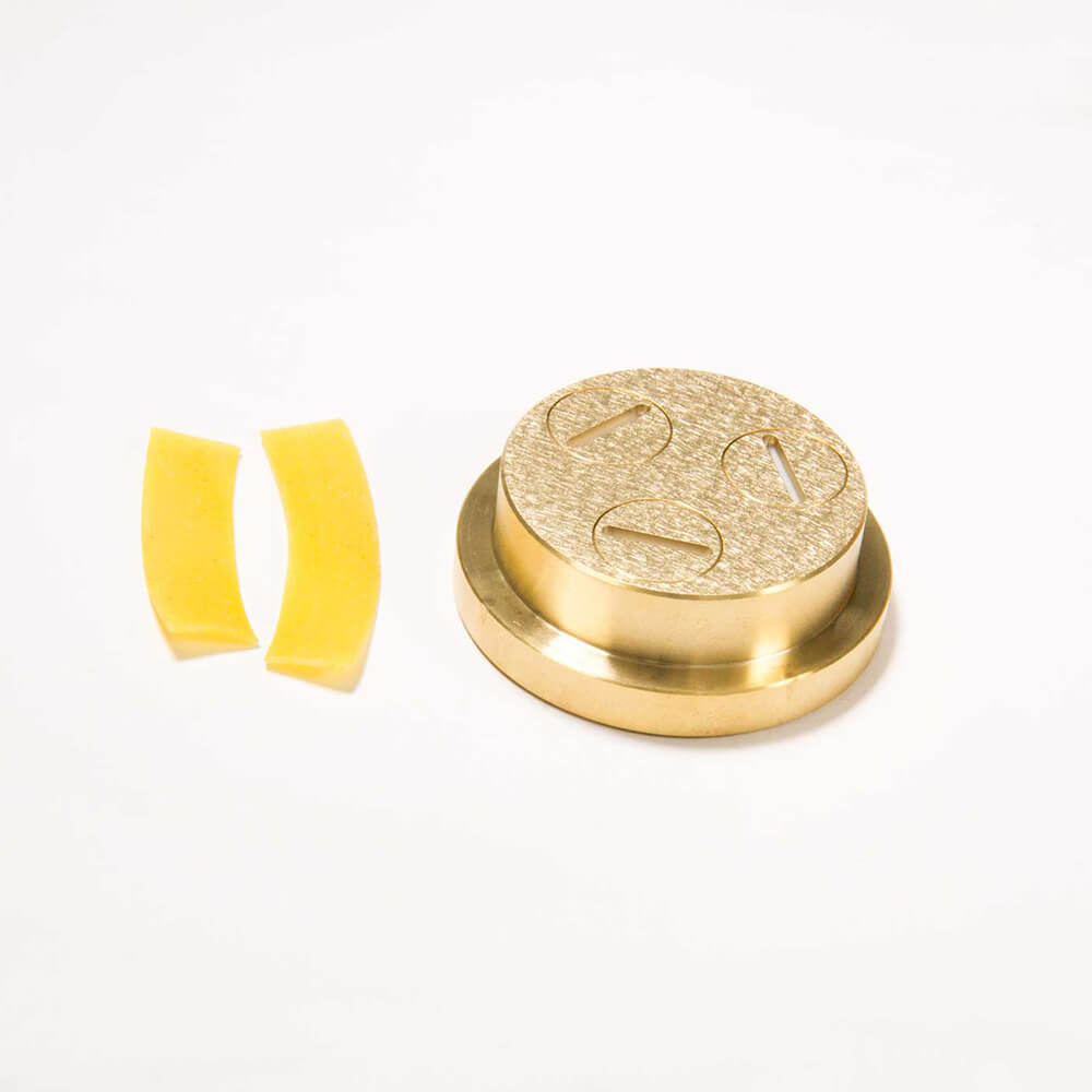 Nudelmatrize Nr. 22 für Bandnudeln neben zwei Bandnudeln vor einem weißen Hintergrund.