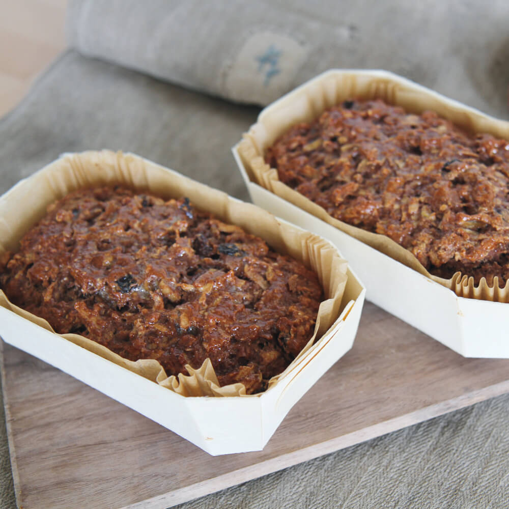 Rezept für Apfelbrot Zwei frische Apfelbrote, gebacken in einer Holzbackform auf einem Backschieber serviert