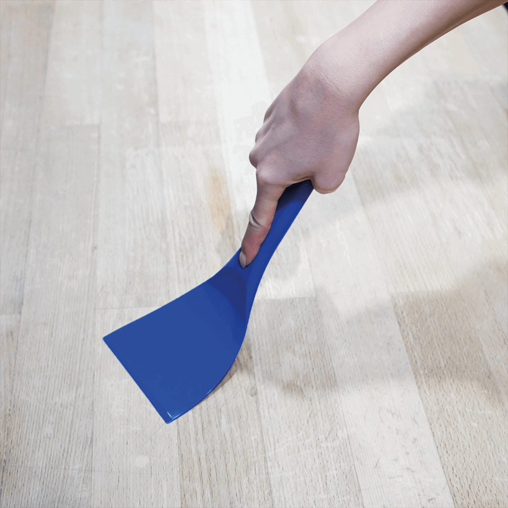 Blauer Teigspachtel in der Anwendung auf einer Arbeitsplatte.