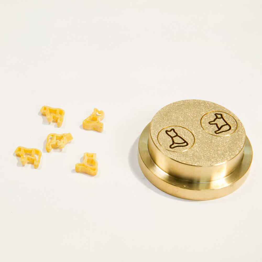 Matrize Nr. 500 - Katze und Kuh Nudelmatrize Nr. 500 für Katzen- und Kuh-Nudeln neben einigen Kuh- und Katzen-Nudeln vor einem weißen Hintergrund.