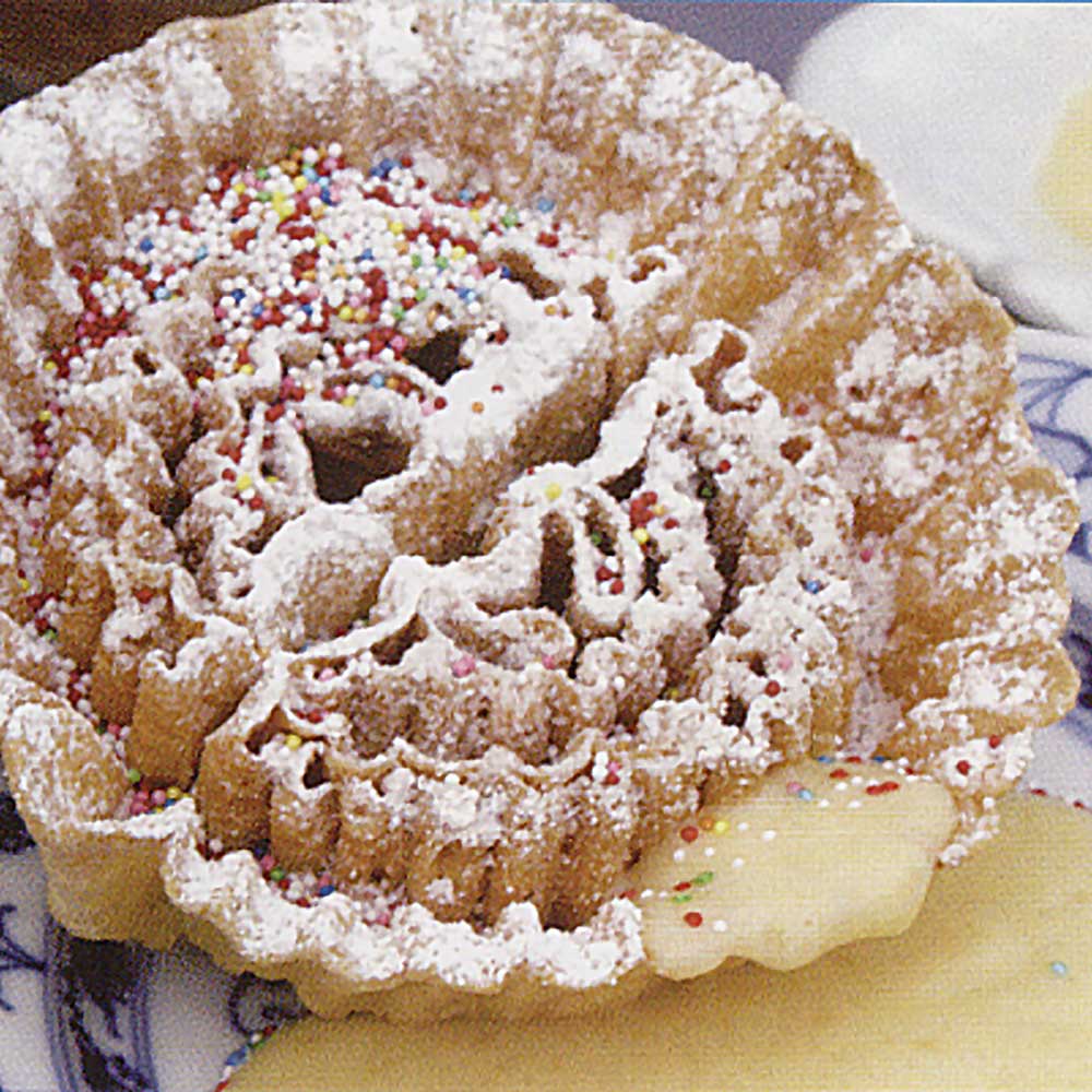 Frittiertes Rosenküchle, das mit Puderzucker und bunten Streuseln dekoriert wurde