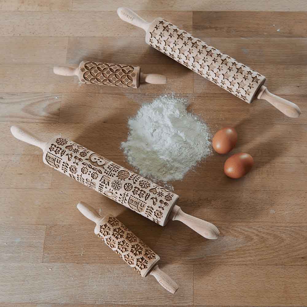 Teigroller mit Motiv Verschiedene Wellholze mit Motiven auf einer Arbeitsfläche mit Mehl und zwei Eier