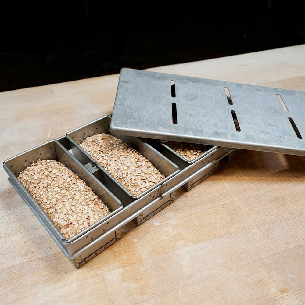 4-teilige Toastbrotform 4-teilige Toastbrotform gefüllt mit Vollkornbroten. Der Deckel ist seitlich angelehnt, auf einer Küchenarbeitsplatte