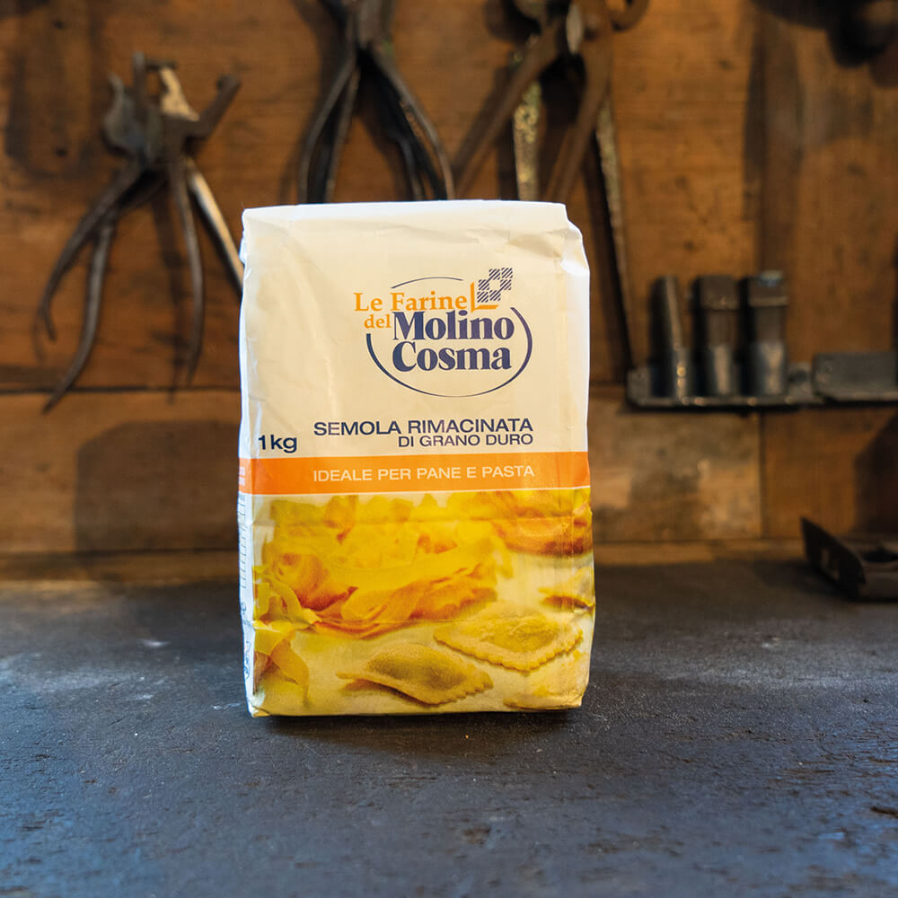 Semola Rimacinata 1kg Mehlpackung mit Aufschrift Le Farine del Molino Cosma, Semola Rimacinata Di Grano Duro 1kg, Ideale per Pane e Pasta. Unterhalb des Textes ist noch ein Bild von fertigen Nudeln und Raviol zu sehen.