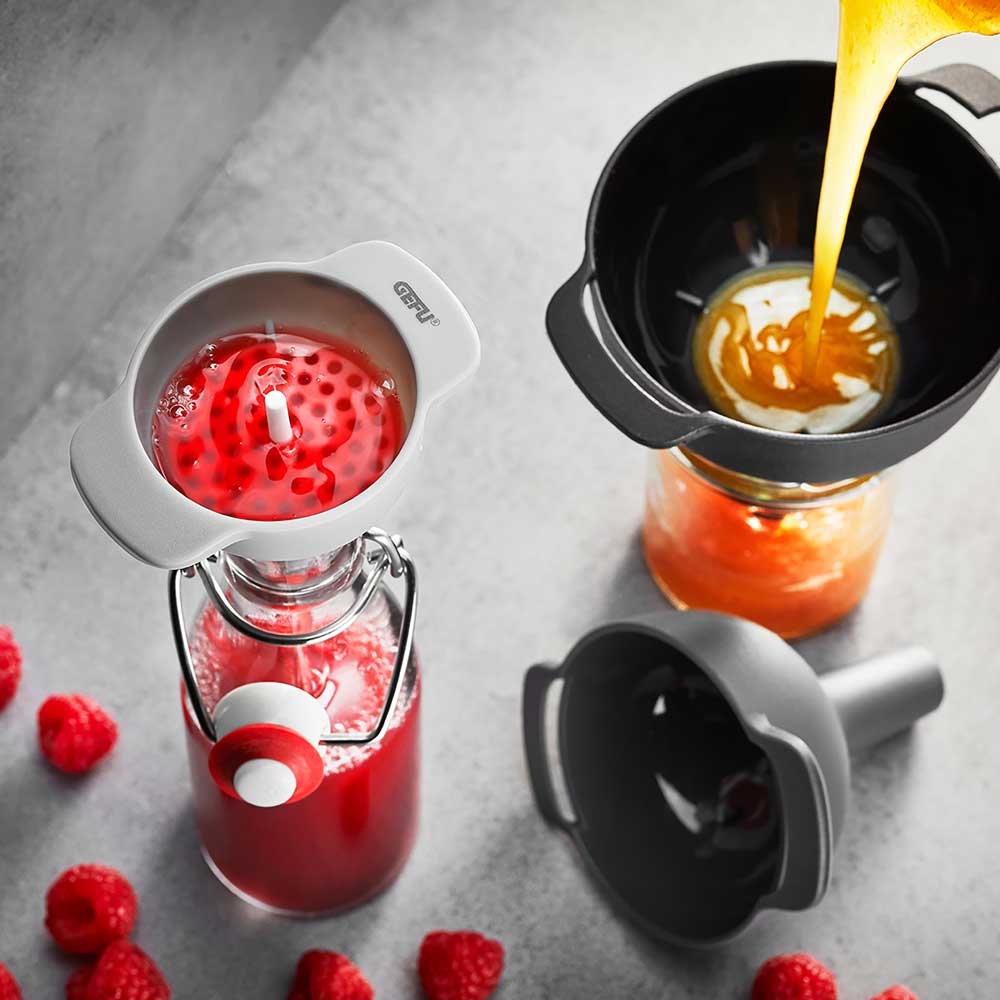 3-teiliges Trichter-Set Trichter-Set in der Anwendung. Die Trichter sind in verschiedene Flaschen eingeführt, es werden Flüssigkeiten eingegossen, auf einer Küchenarbeitsplatte.