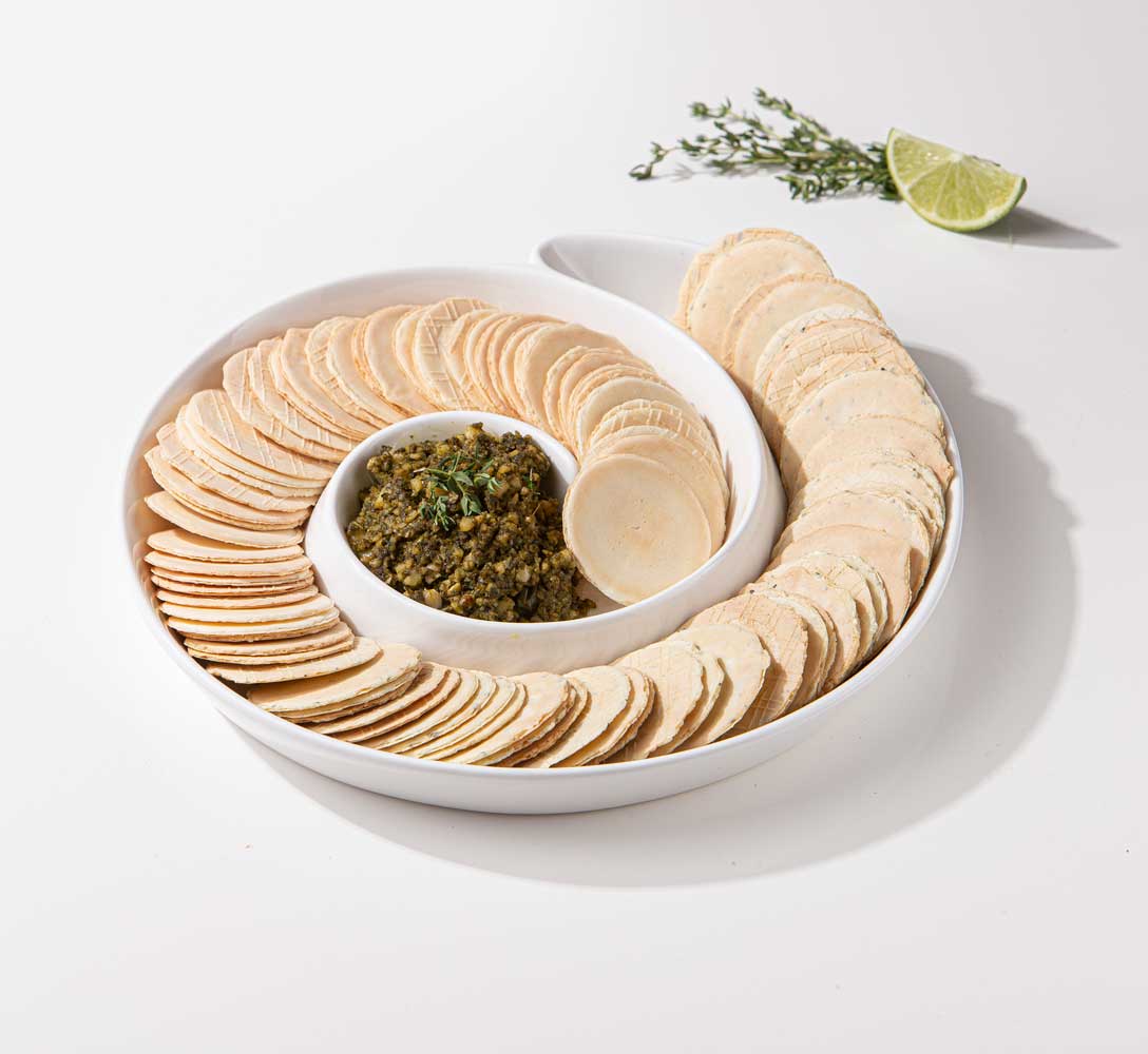 Servierteller Spiralr in weiß, gefüllt mit runden Keksen und in der Mitte ist ein grüner Dip