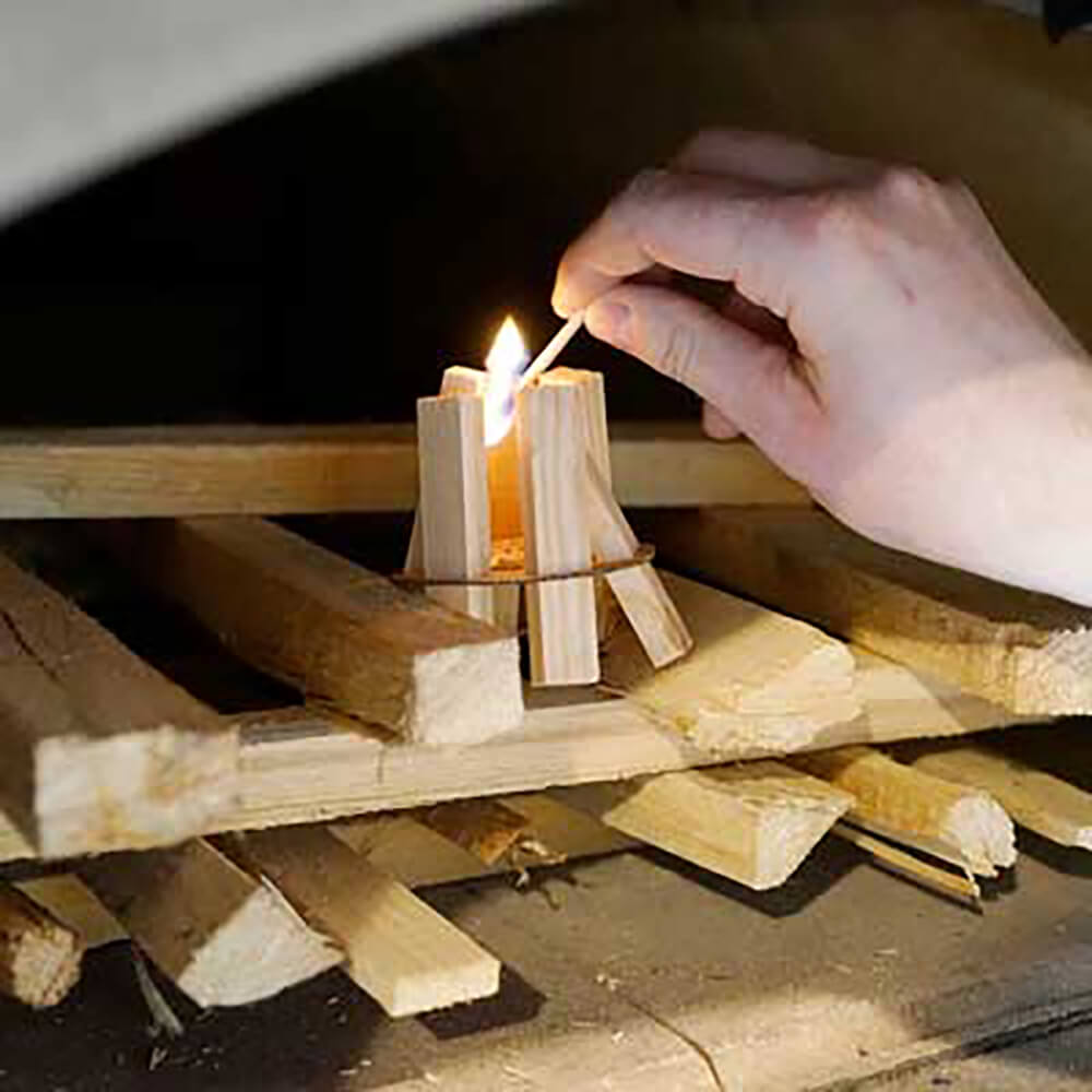 Gestapeltes Holz im Holzbackofen. Die Hölzer vom Feuerkit werden angezunden