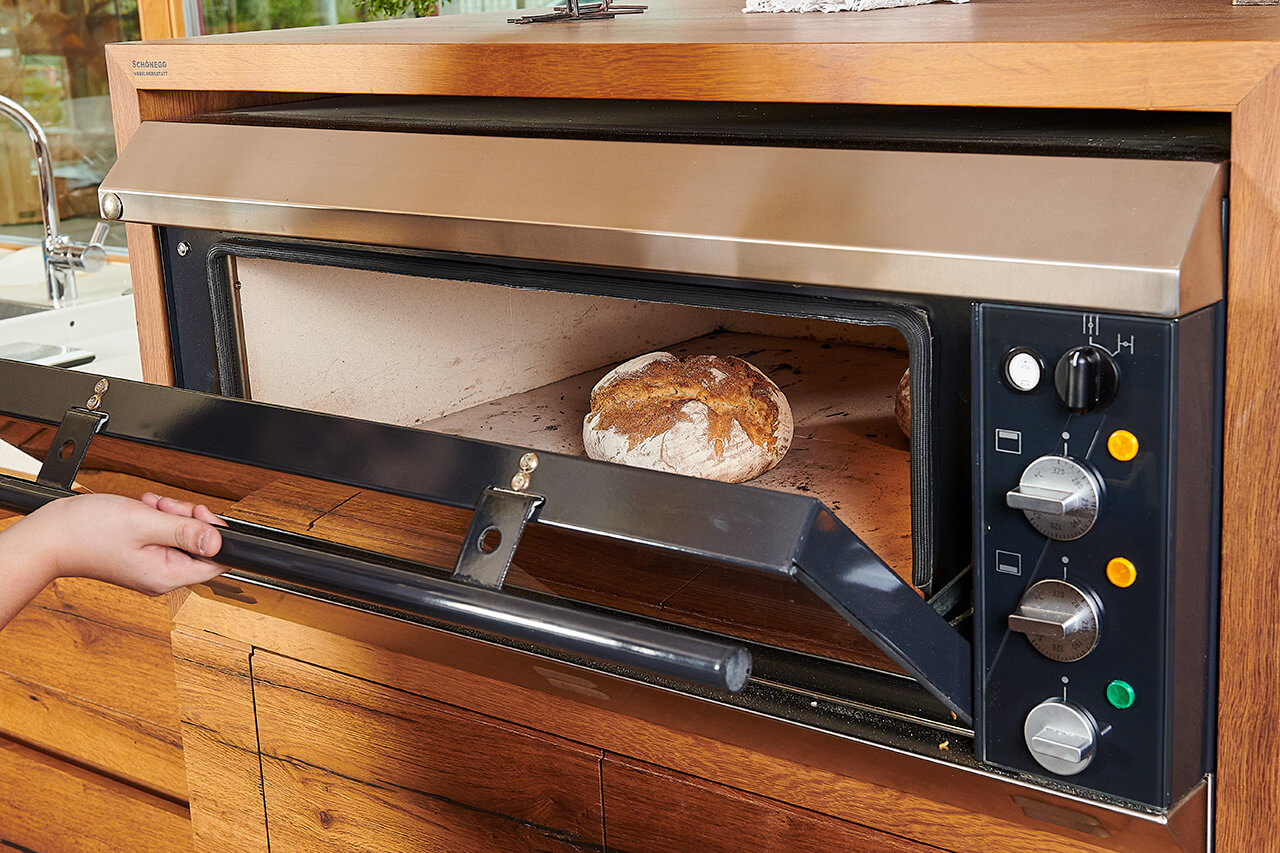 Elektro-Steinbackofen Elektro-Steinbackofen mit offener Tür und fertig gebackenem Brot.