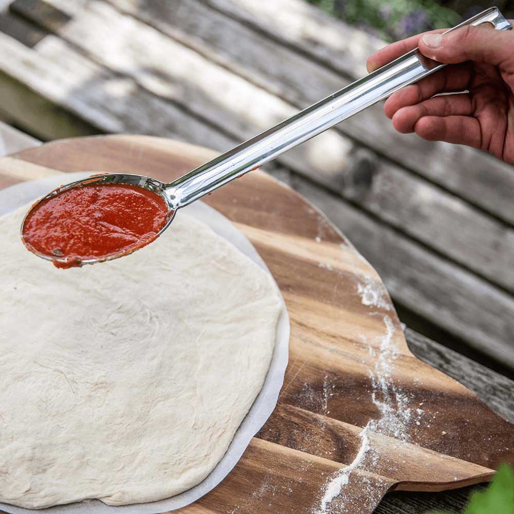 Pizzasugo-Löffel mit Tomatensoße über Pizzaboden